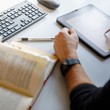 Ein kvw-Mitarbeiter liest in einem Gesetzt und macht Notizen auf dem iPad.