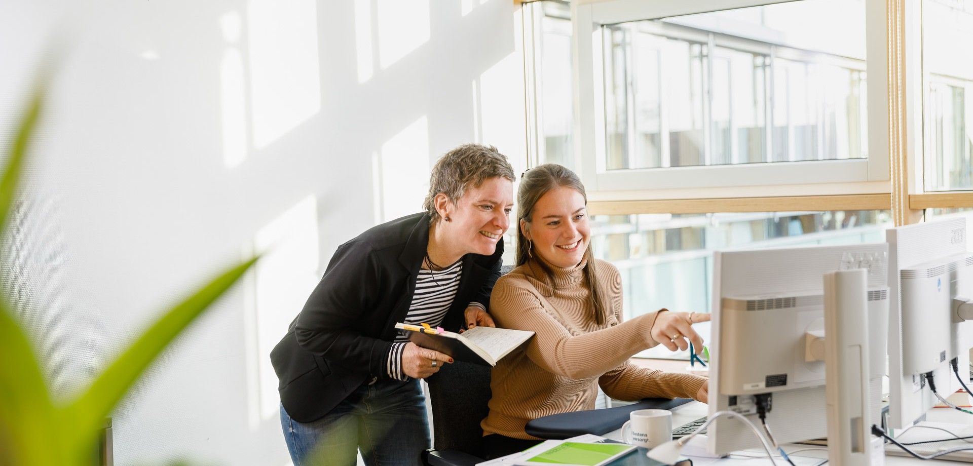 Zwei Kolleginnen vor einem Bildschirmarbeitsplatz