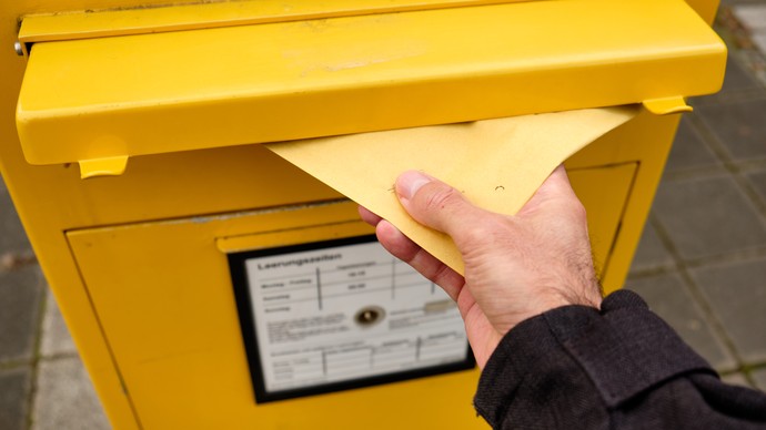 Ein Brief wird in einen Briefkasten geworfen