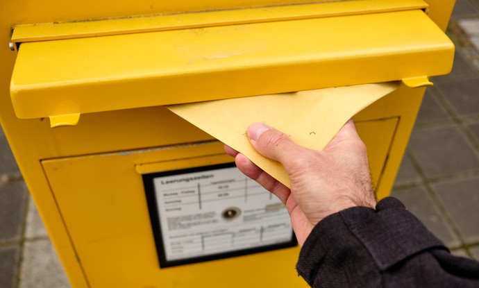 Brief wird in Briefkasten geworfen