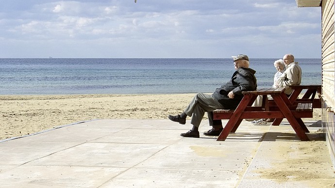 Rentner:innen auf einer Parkbank am Strand