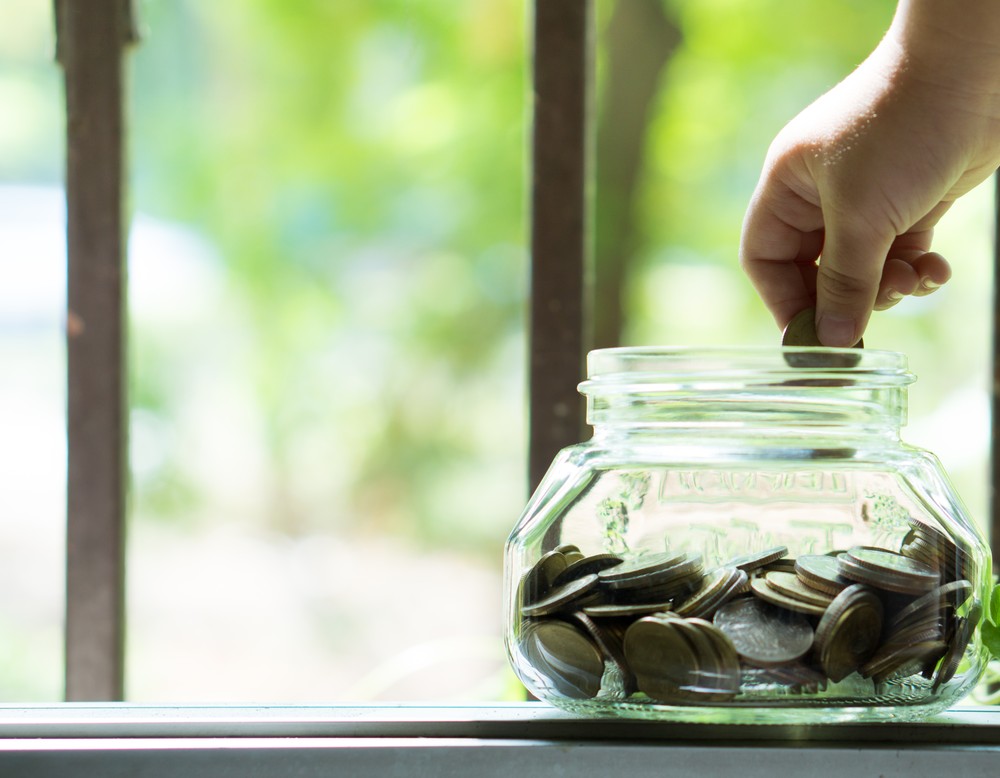 Glas wird mit Geldmünzen gefüllt. Symbolisch für die Vorsorge für Pensionslasten der kvw.